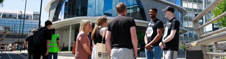 This image shows the exterior of a Northumbria University building in Newcastle, featuring a modern glass facade