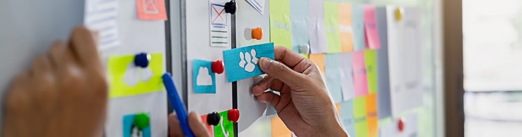 Marketing team using a physical whiteboard with sticky notes and icons to organize